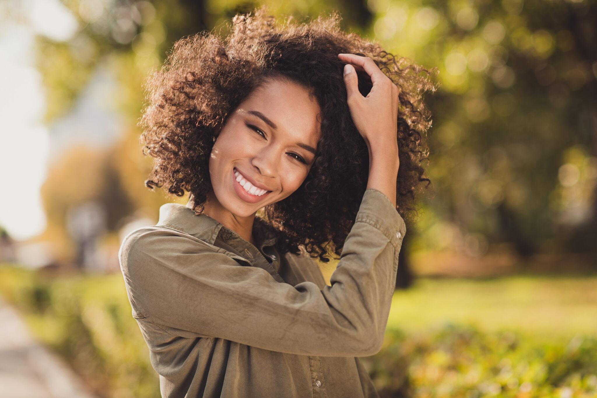 Portrait Of Gorgeous Positive Curly Hairstyle Dark Skin Person Hand Touch Hair Toothy Smile Enjoy Weekend Outdoors