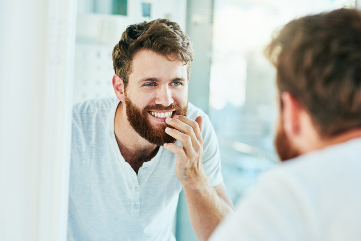 Cropped shot of a handsome young man looking at his teeth in the bathroom mirror